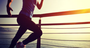 Young Fitness Woman Running On Sunrise Seaside Boardwalk